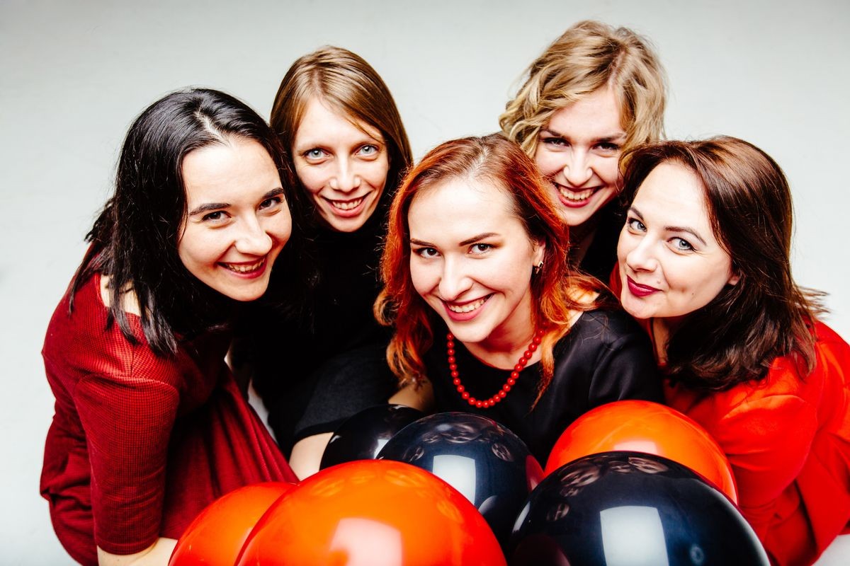 Group of five smiling women in red and black dress holding balloons and sitting together. Celebrate and people, fun, hen-party concept.